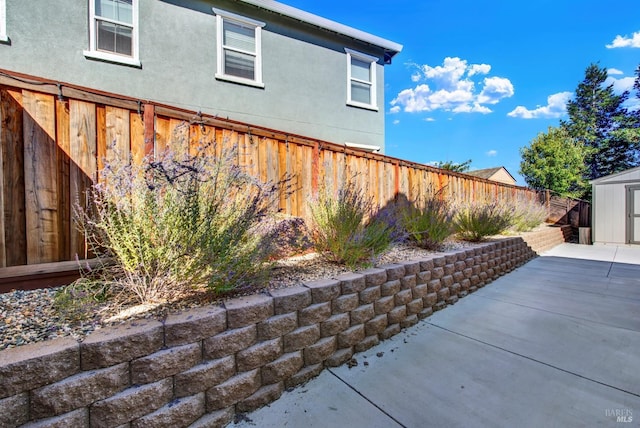 view of side of home with a storage unit and a patio