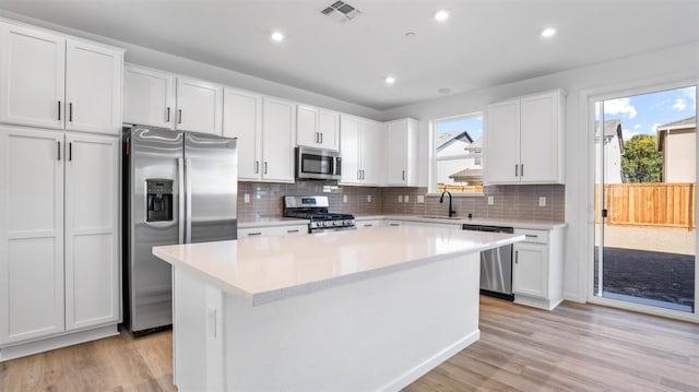 kitchen featuring sink, a kitchen island, a healthy amount of sunlight, stainless steel appliances, and white cabinets