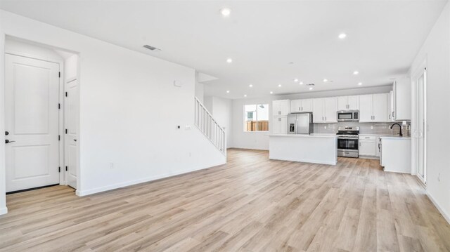 kitchen featuring a kitchen island, tasteful backsplash, sink, white cabinets, and stainless steel appliances