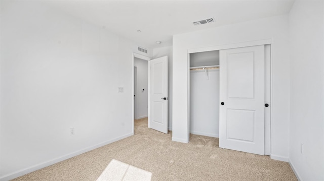 unfurnished bedroom with light carpet and a closet