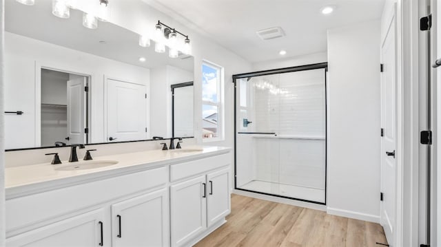 bathroom with wood-type flooring, vanity, and a shower with shower door