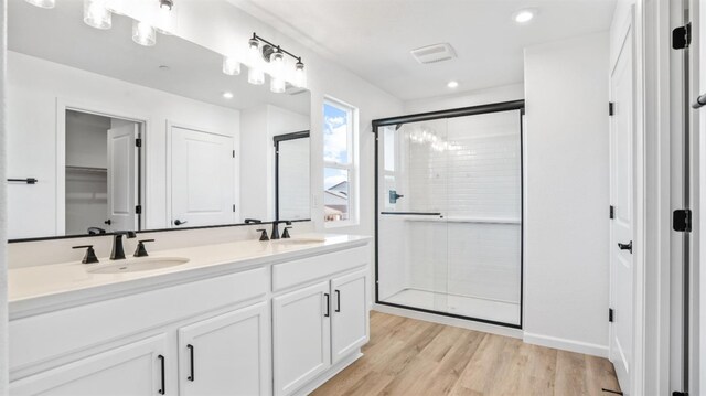 bathroom with vanity, a shower with shower door, and wood-type flooring