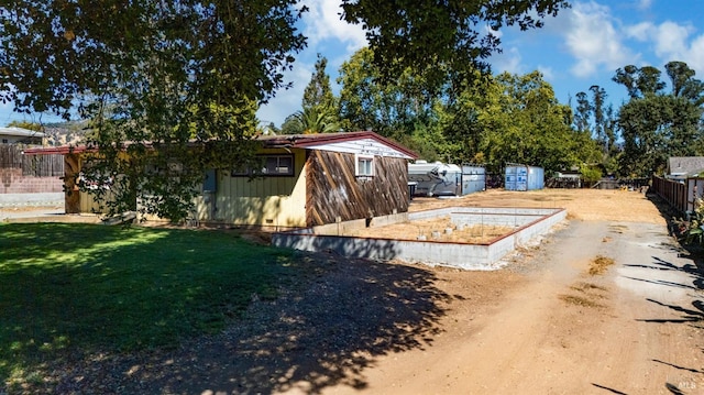 view of yard featuring dirt driveway and fence