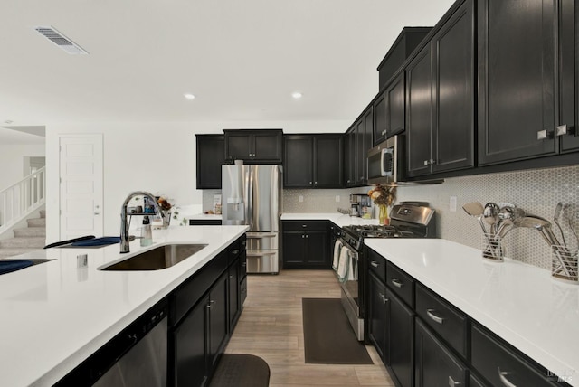 kitchen featuring sink, appliances with stainless steel finishes, decorative backsplash, and light hardwood / wood-style floors