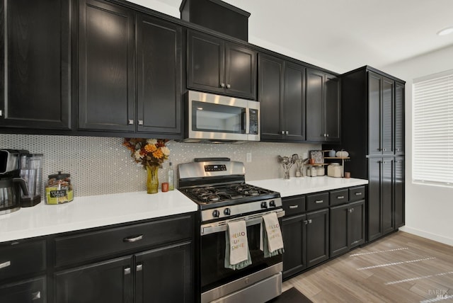 kitchen with appliances with stainless steel finishes, decorative backsplash, and light hardwood / wood-style flooring