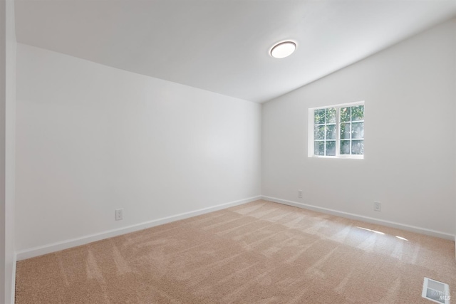 unfurnished room featuring vaulted ceiling and light colored carpet