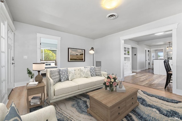 living area with baseboards, visible vents, and wood finished floors