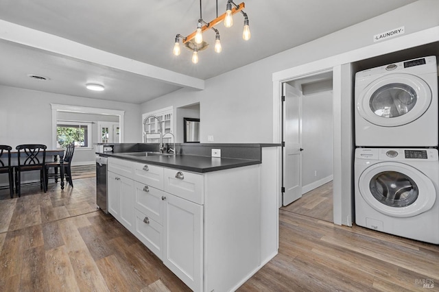 kitchen featuring dark wood-style flooring, a sink, stacked washing maching and dryer, and dark countertops