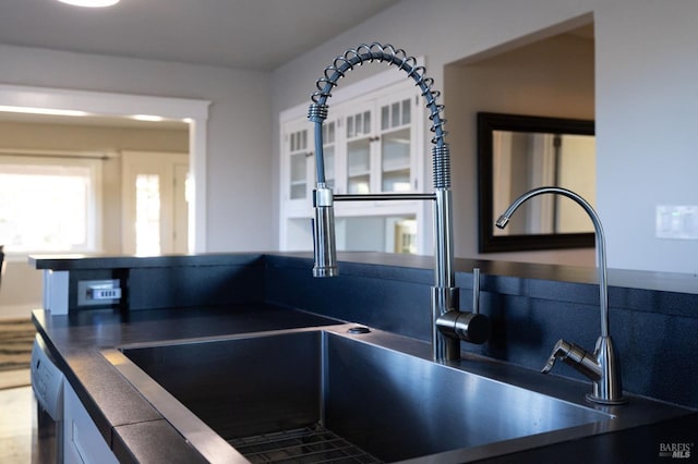 kitchen with dishwashing machine, a sink, and dark countertops