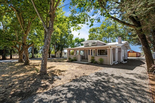 view of front of home with a chimney, stucco siding, covered porch, and driveway