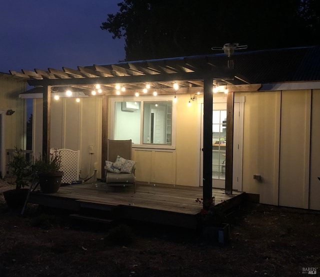 back of house at twilight featuring board and batten siding, a pergola, and a deck