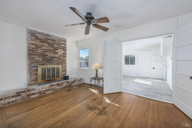 unfurnished living room with hardwood / wood-style floors, a brick fireplace, and ceiling fan