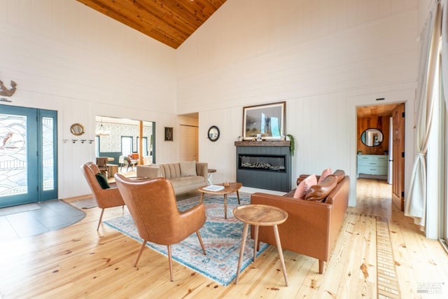 living room with wood walls, high vaulted ceiling, light hardwood / wood-style floors, and wooden ceiling