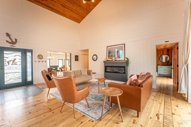 living room featuring wood ceiling, wooden walls, high vaulted ceiling, and light hardwood / wood-style floors