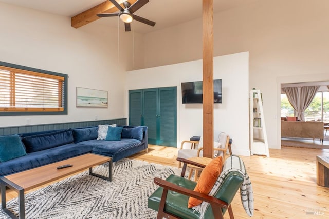 living room with ceiling fan, vaulted ceiling with beams, and light hardwood / wood-style floors