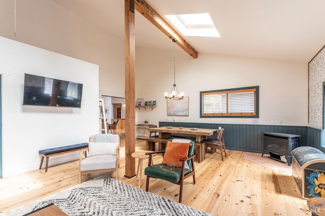 living area with a wood stove, an inviting chandelier, a skylight, and light hardwood / wood-style floors