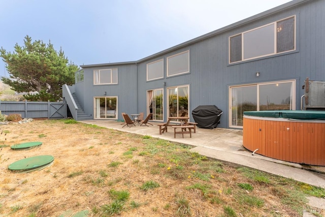 back of house with a hot tub and a patio