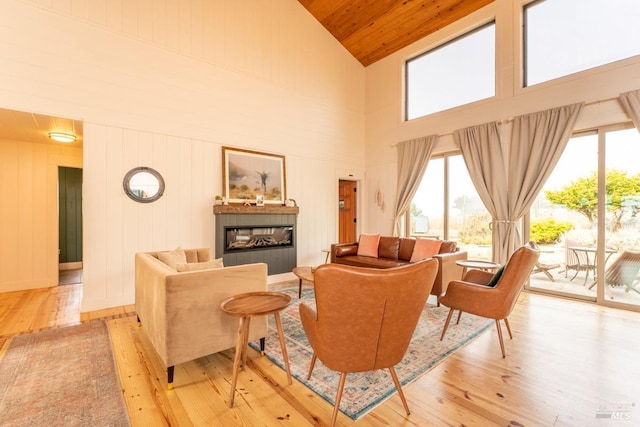 living room with high vaulted ceiling, wood walls, and light hardwood / wood-style floors