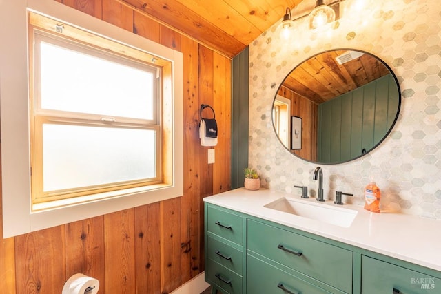 bathroom with wooden ceiling, vanity, and wood walls