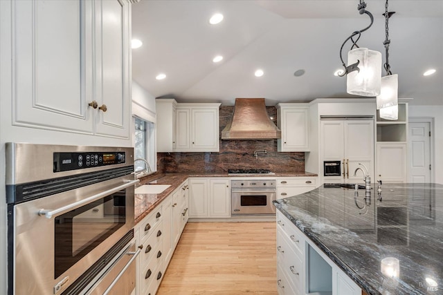 kitchen with white cabinetry, stainless steel oven, and custom exhaust hood