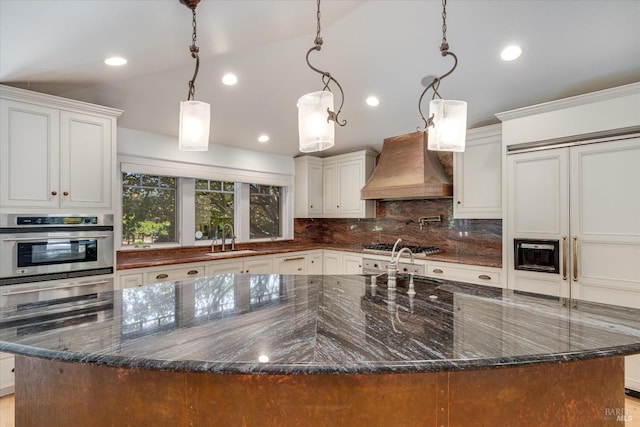 kitchen featuring pendant lighting, a large island, appliances with stainless steel finishes, custom range hood, and dark stone countertops