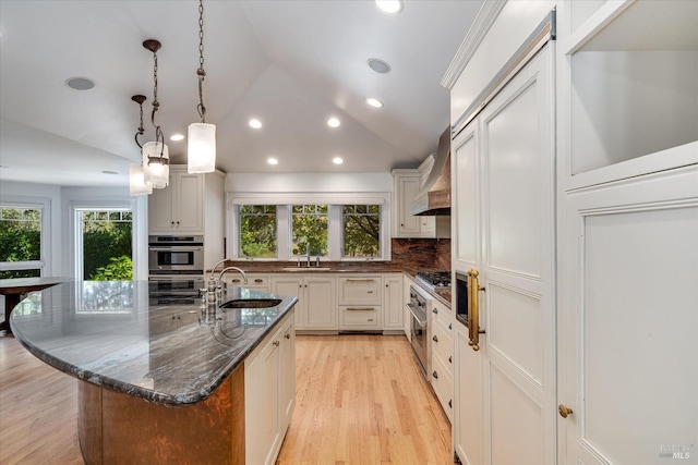 kitchen with a center island, sink, decorative light fixtures, dark stone counters, and lofted ceiling