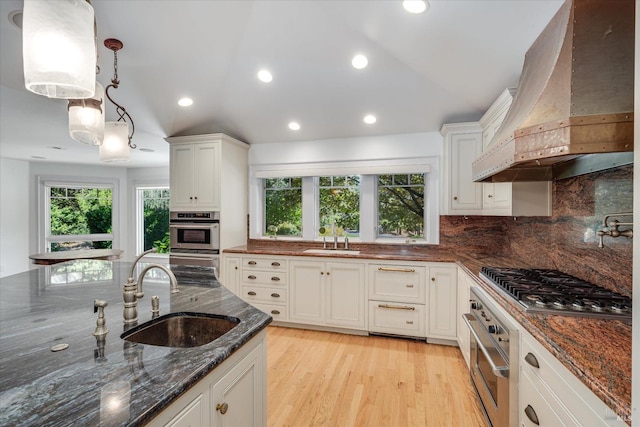 kitchen featuring white cabinets, custom exhaust hood, sink, hanging light fixtures, and stainless steel gas cooktop