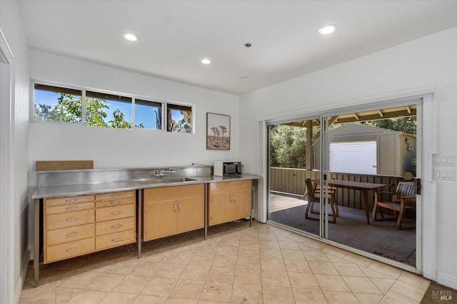 kitchen featuring stainless steel counters, sink, light brown cabinetry, and light tile patterned floors