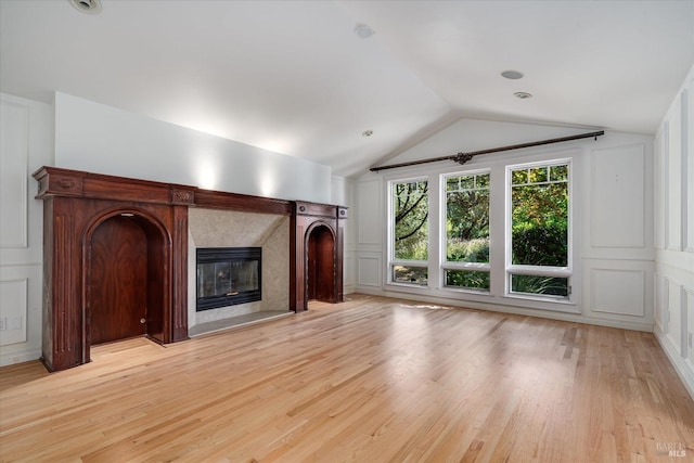 unfurnished living room featuring light wood-type flooring, a high end fireplace, and lofted ceiling