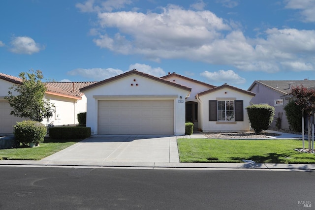 mediterranean / spanish house featuring a garage, driveway, a front lawn, and stucco siding