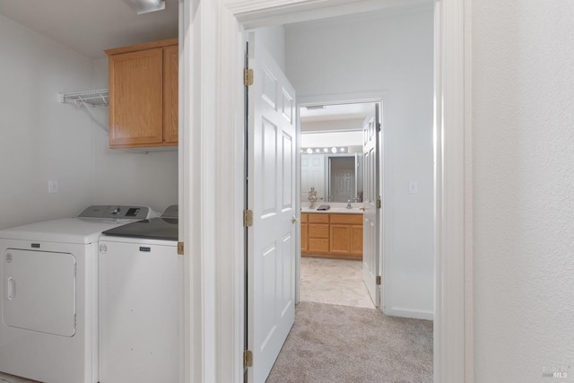 washroom with light colored carpet, cabinet space, a sink, and washing machine and clothes dryer