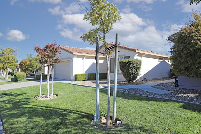 view of front facade featuring an attached garage, a tile roof, driveway, stucco siding, and a front yard