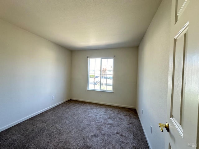 carpeted spare room featuring a textured ceiling and baseboards