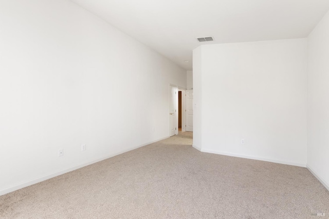 empty room featuring baseboards, visible vents, and light colored carpet