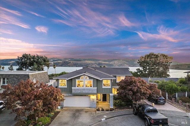 view of front of property featuring fence, a mountain view, concrete driveway, a shingled roof, and a garage