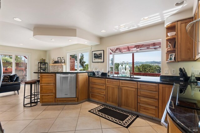 kitchen featuring light tile patterned floors, kitchen peninsula, stainless steel dishwasher, and sink