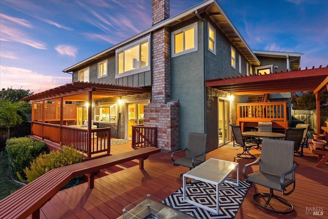 back house at dusk featuring a pergola and a deck