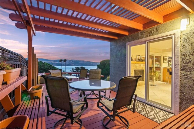 deck at dusk with a pergola and a water and mountain view