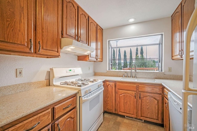 kitchen with white appliances, light stone counters, and sink