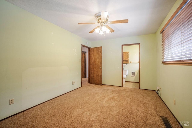 unfurnished bedroom featuring light colored carpet, ensuite bathroom, and ceiling fan