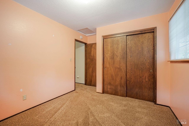 unfurnished bedroom with a closet, light carpet, and a textured ceiling