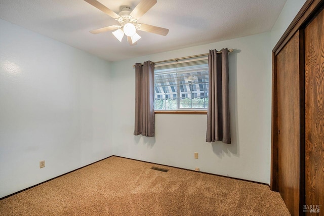 carpeted spare room with a textured ceiling and ceiling fan