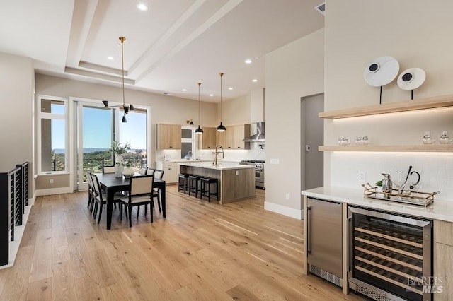 dining area with beverage cooler, sink, and light wood-type flooring