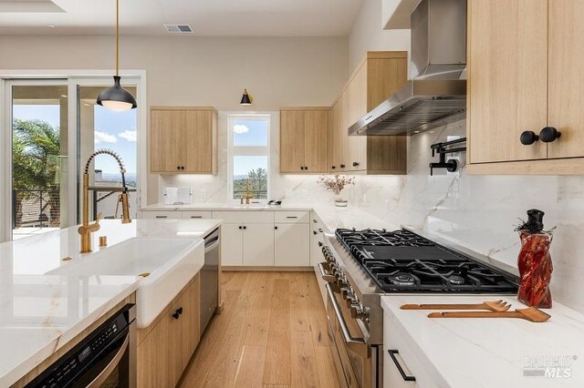 kitchen featuring white cabinets, hanging light fixtures, light hardwood / wood-style flooring, stainless steel appliances, and wall chimney exhaust hood