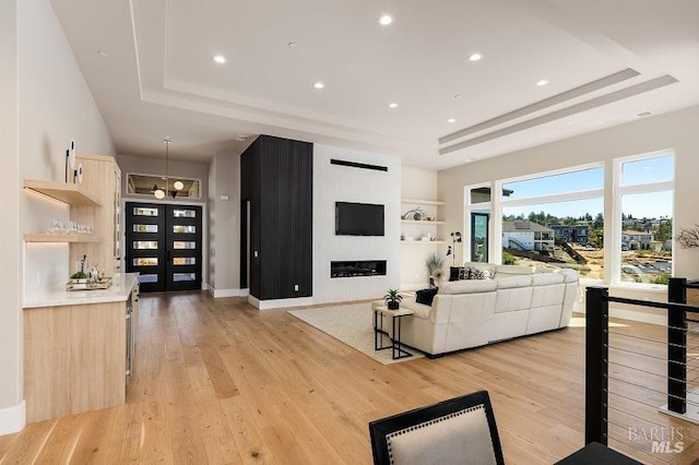 living room featuring a raised ceiling and light hardwood / wood-style floors