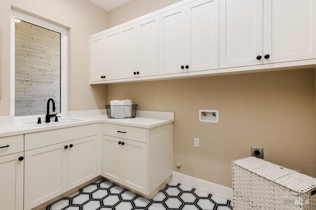 washroom with hookup for a washing machine, hookup for an electric dryer, cabinets, and sink