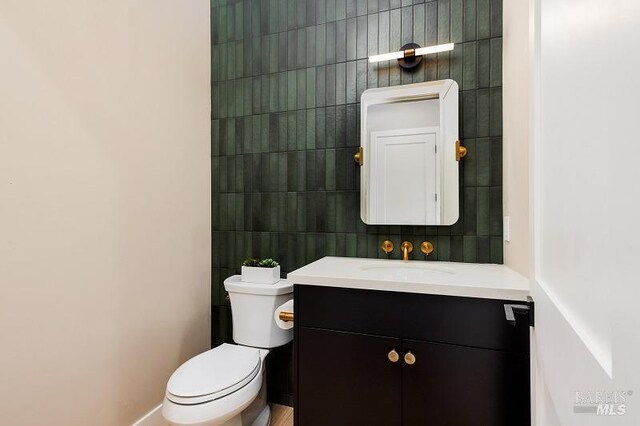 bathroom with vanity, toilet, tile walls, and decorative backsplash