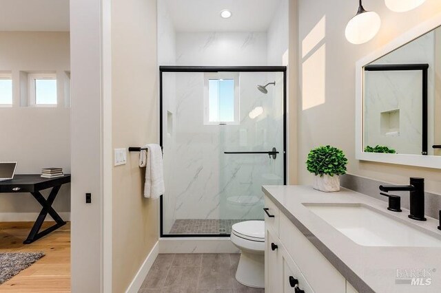 bathroom featuring vanity, toilet, an enclosed shower, and hardwood / wood-style floors