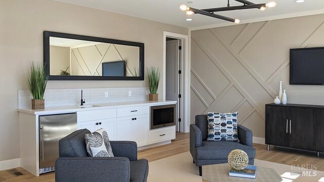 living room with wet bar and light wood-type flooring