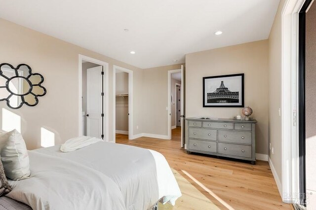 bedroom featuring a closet, a spacious closet, and light wood-type flooring